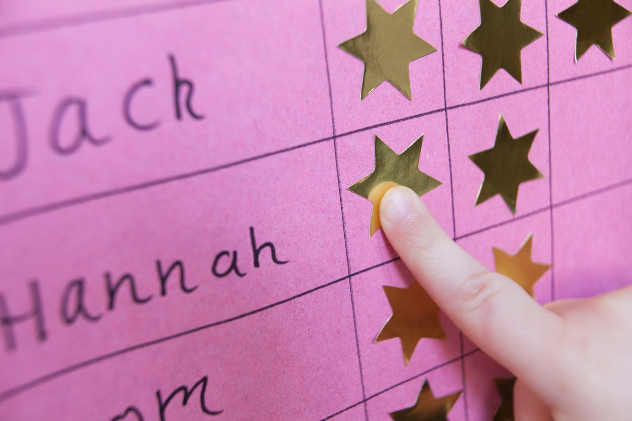 Closeup of a child putting a gold sticker next to his name on a chart