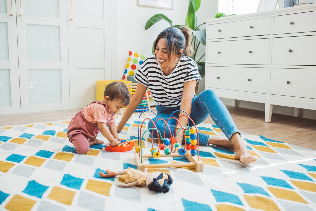 Mother playing on the ground with sensory toys with her toddler