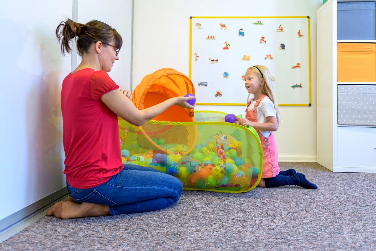 An RBT playing with a young girl with autism in a sensory room with a ball pit