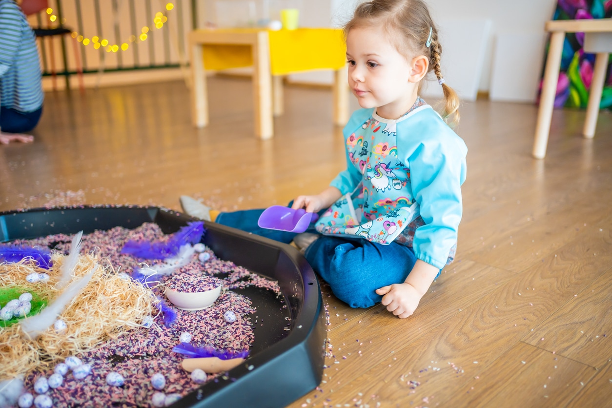 A young girl playing with a sensory pool during her ABA therapy session