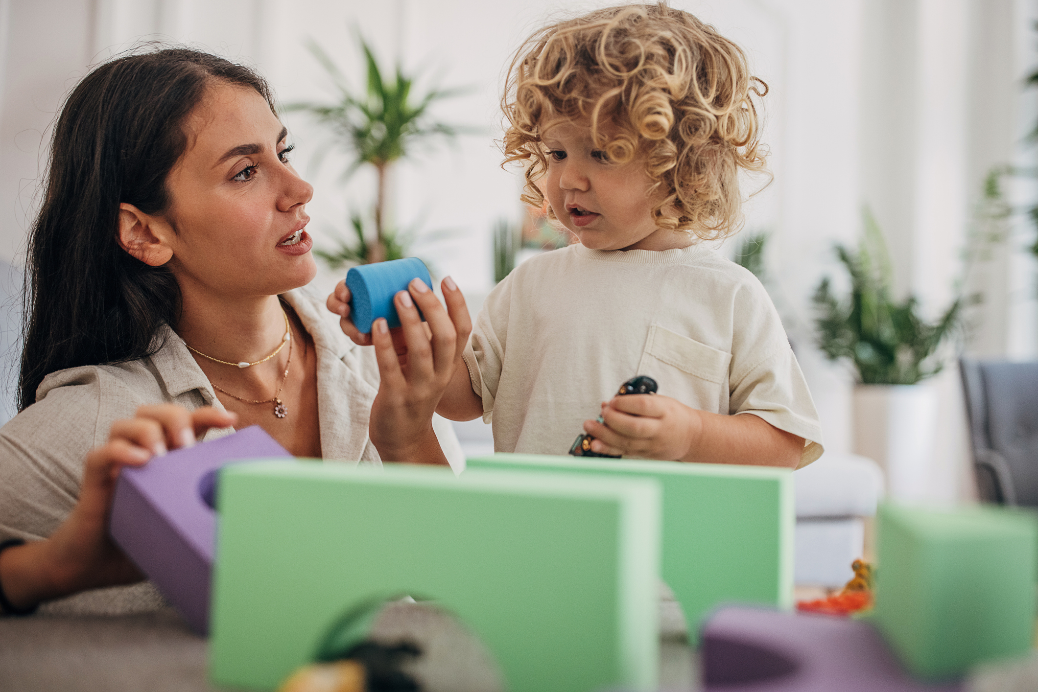 BCBA plays with building blocks with a young boy with sensory issues and autism